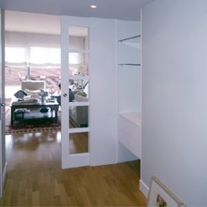 Interior de vivienda diseñado en blanco con suelo de parquet por Vibel Estudi