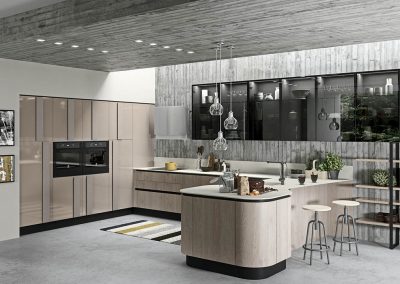 Vista de cocina de la marca Aran. Mueble bajo en color y textura de madera que integra los elementos de la cocina. Mueble en linea curva en forma de L.