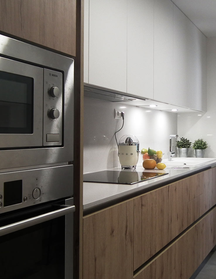 Imagen de cocina equipada con torre de electrodomésticos Bosch. Muebles bajos en color y textura de madera que contrastan con los muebles aereos de color blanco  