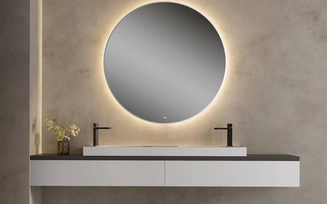 Baño de la marca Fiora. Vista del mueble del lavabo de color blanco con grifos de color negro y espejo redondo de pared de fondo.